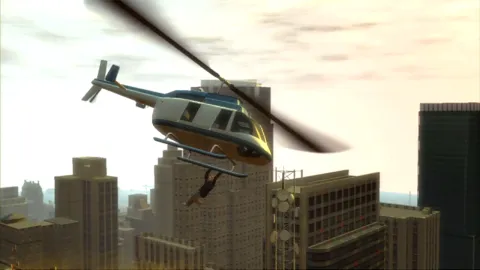 A man hanging from the bottom of a helicopter.