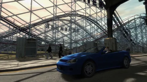 A blue sports car drives past a fairground.