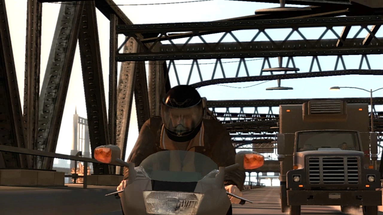 Niko rides a motorbike with a helmet on. A truck is see in in the background.